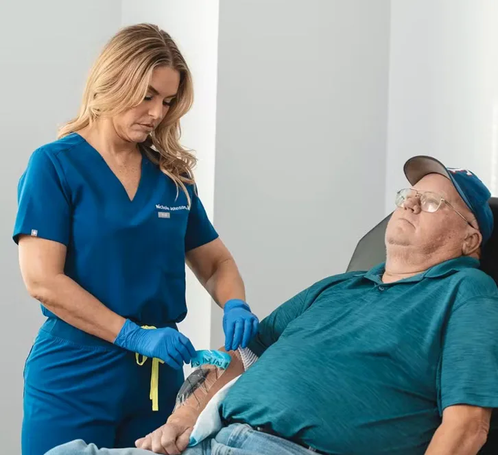 A staff member checking a wound on a patients arm